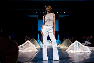 model appearing on stage wearing pants and sleeveless top
