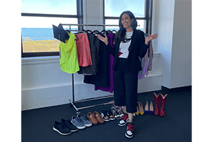 rachel jimenez penca poses in front of a rack of clothes and shoes