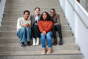 a group of four students pose together on the stairs of the student center