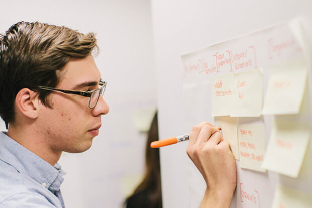 Person at board writing on post-it note