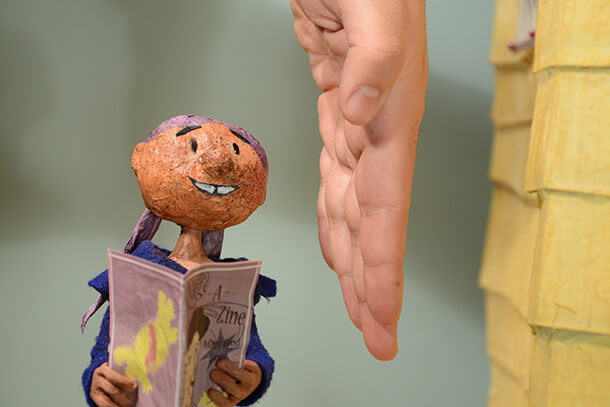 clay character used in animation projects with person's hand