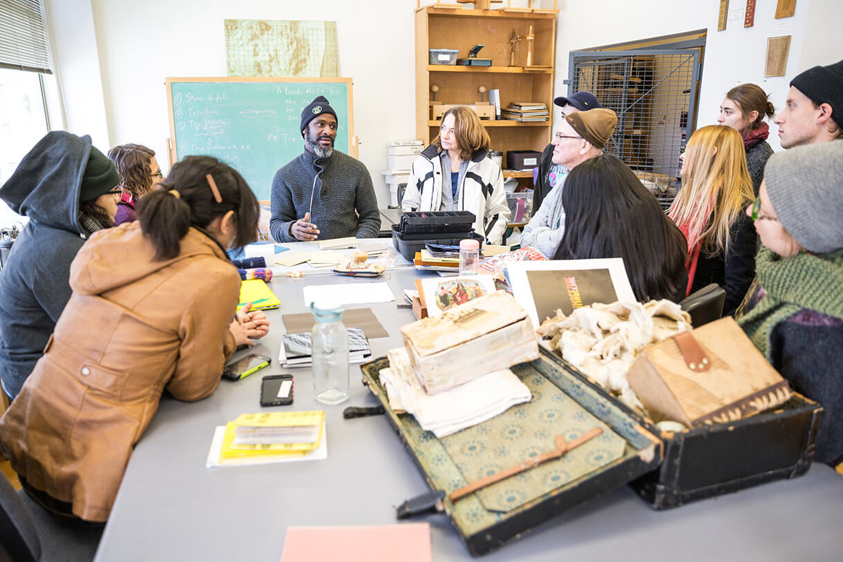 students sitting around desk listening to professor