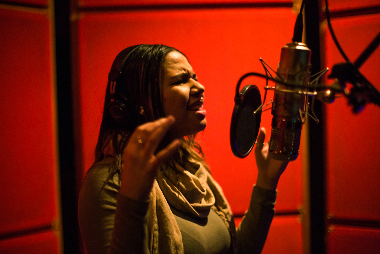 woman in recording studio singing into microphone