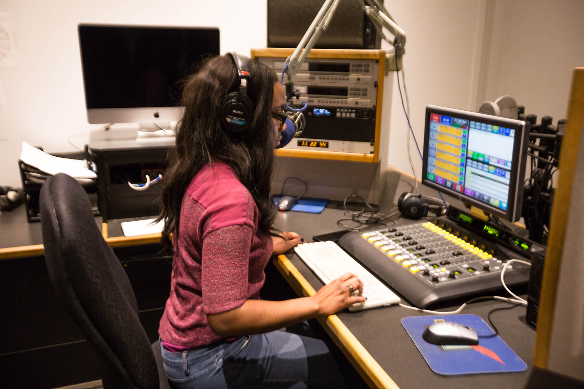 person sitting at controls in radio station