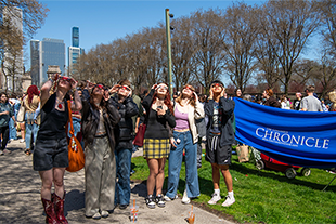 students gather around columbia chronicle banner for eclipse