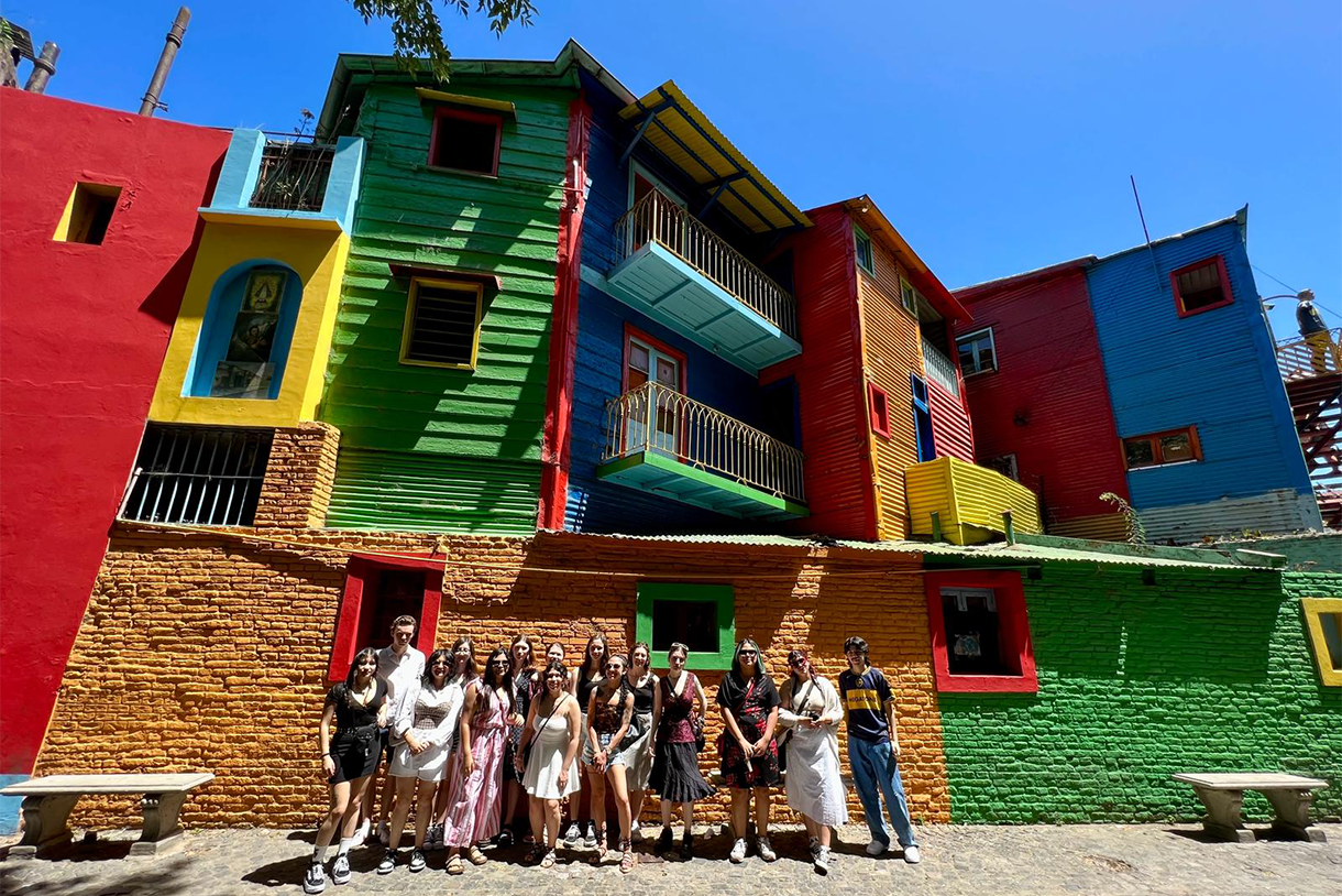 students stand in front of colorful buildings