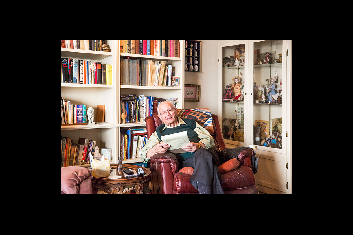 peter berkos sitting in chair in front of bookcases