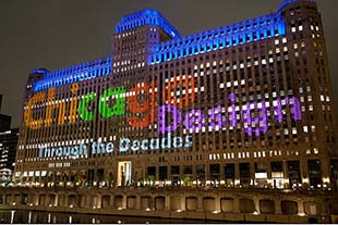 evening photo of merchandise mart with  the words chicago design through the decades illuminated on the building