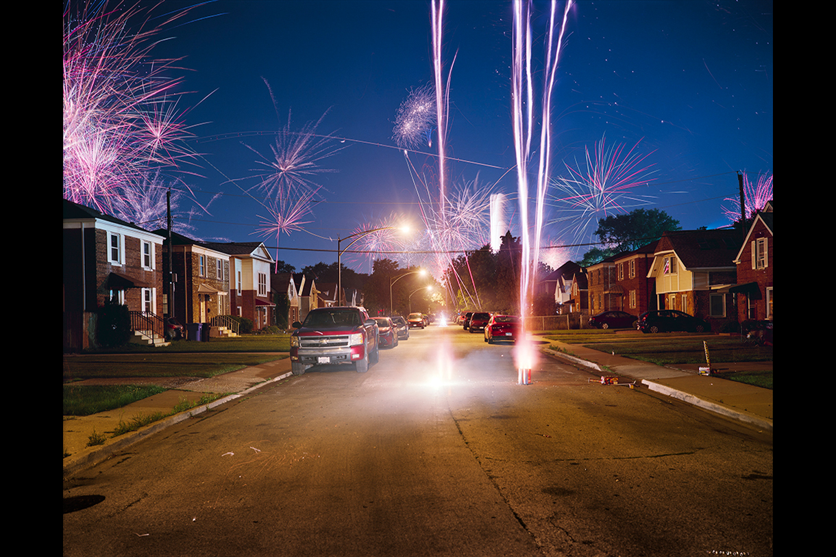street view of fireworks in the night sky in a residential area near Midway