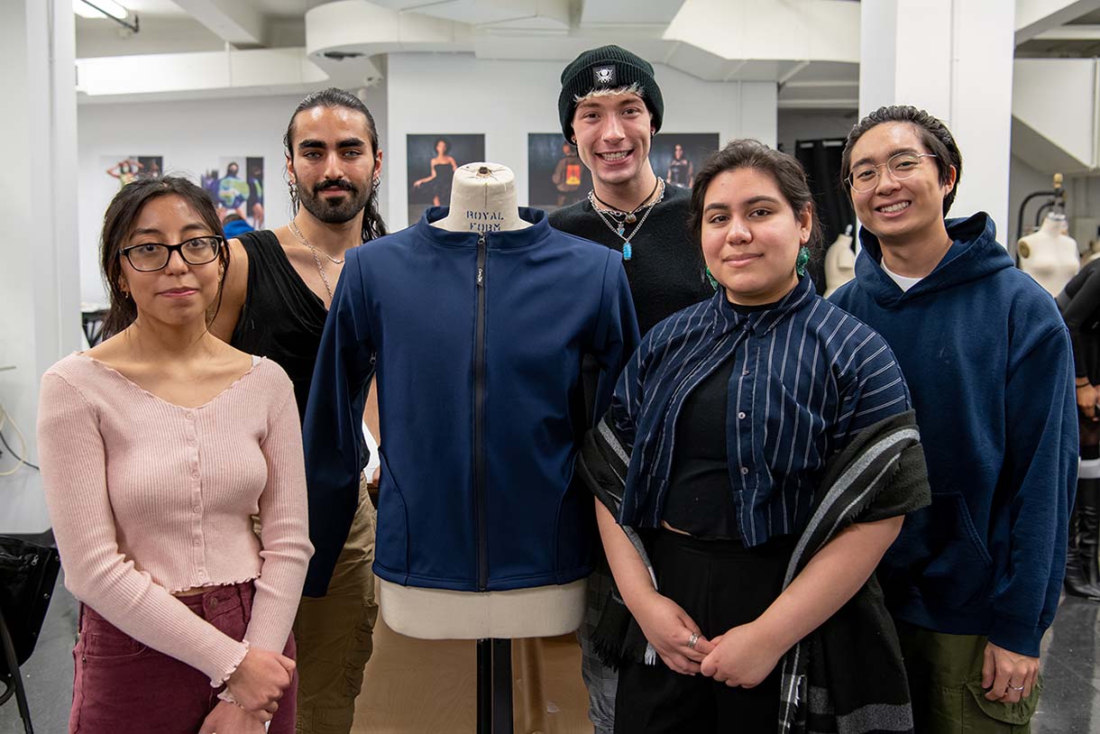 students pose with the blue jacket they designed