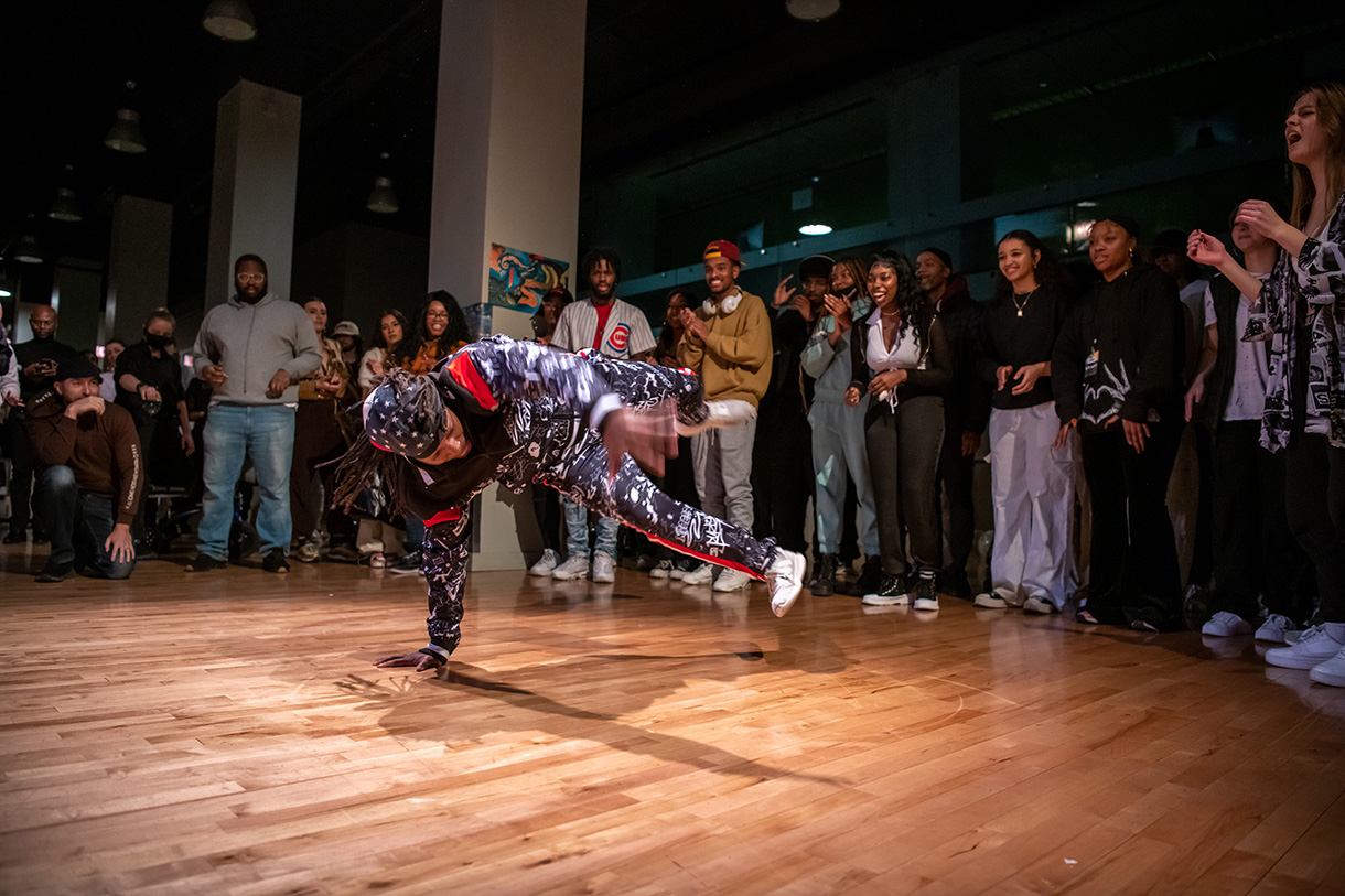 student breakdancing in circle of cheering crowd