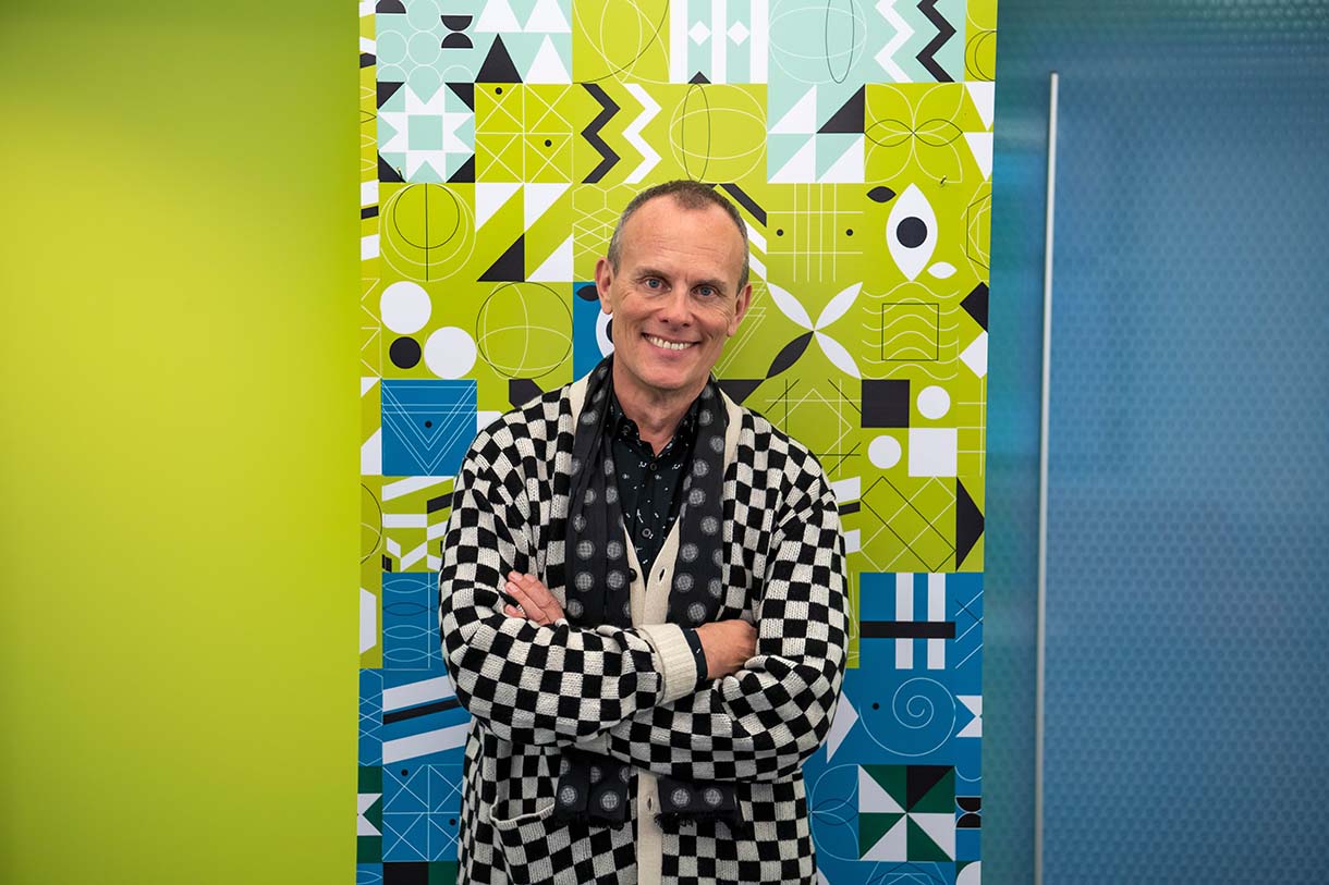 tom eslinger poses in frong of vibrant green and black artwork