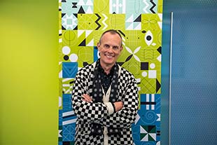 tom eslinger poses in frong of vibrant green and black artwork