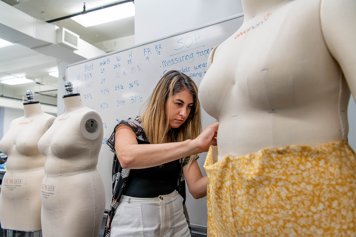 person draping fabric around mannequin