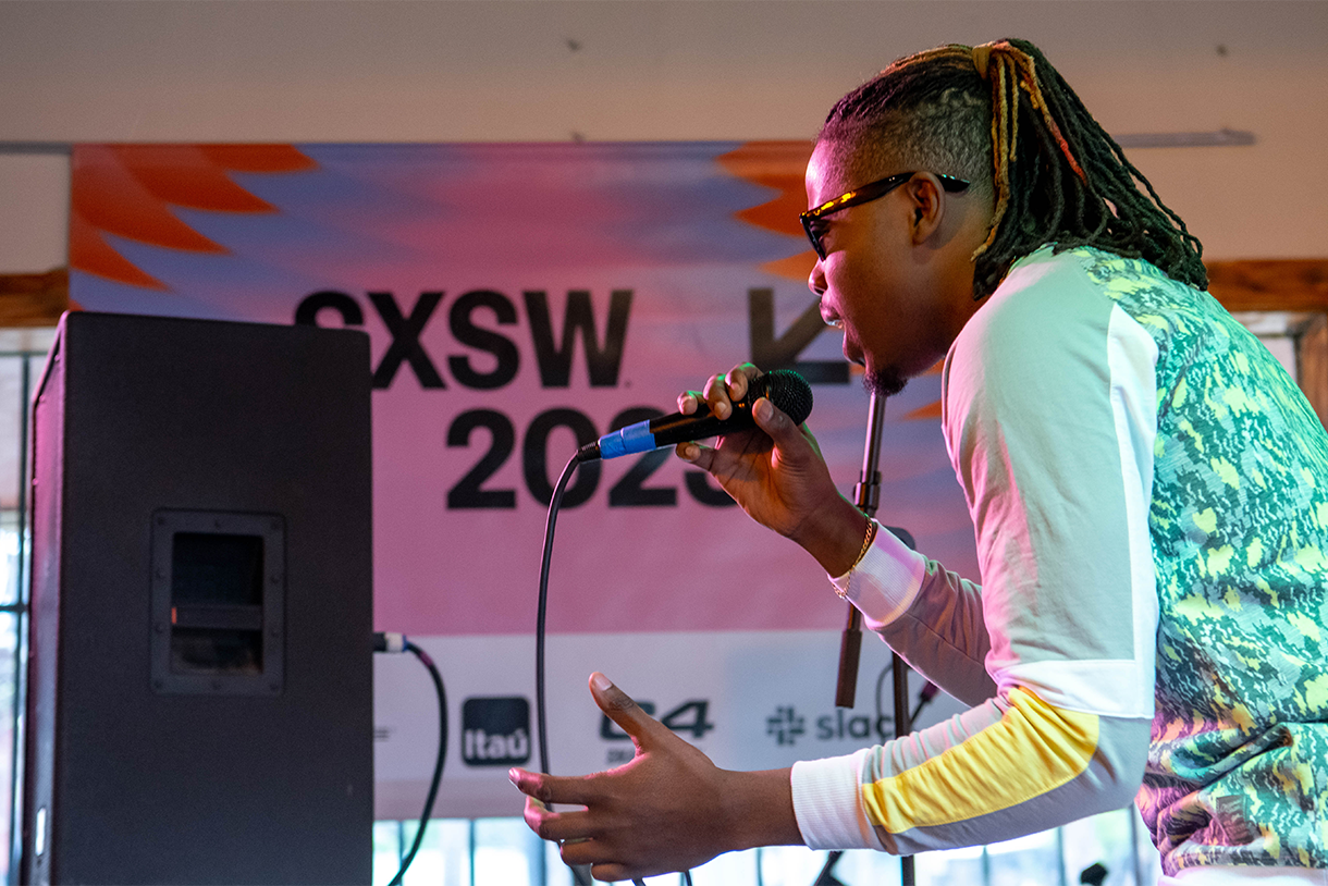 performer on stage with microphone and sxsw signage in back