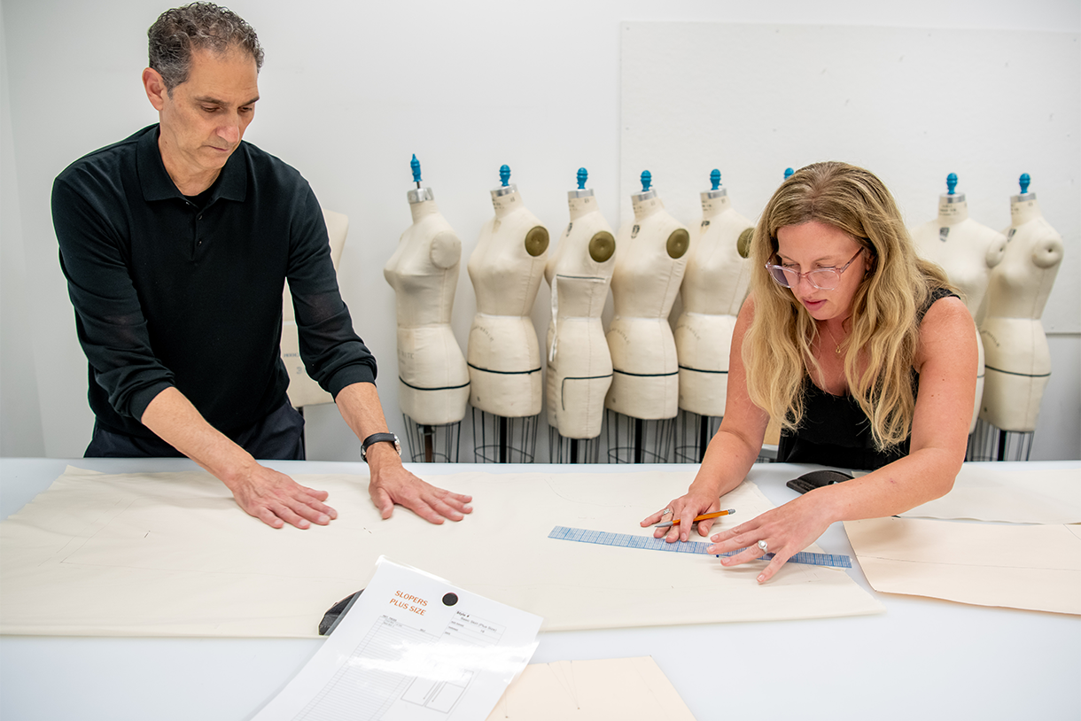 two people measuring and working with patterns at table