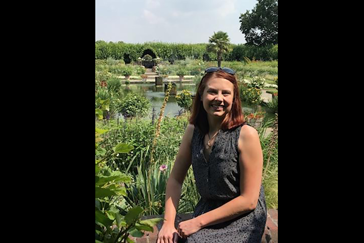 Brittney Sherman sitting in front of a pond at Kensington Palace while on a work trip to London. 